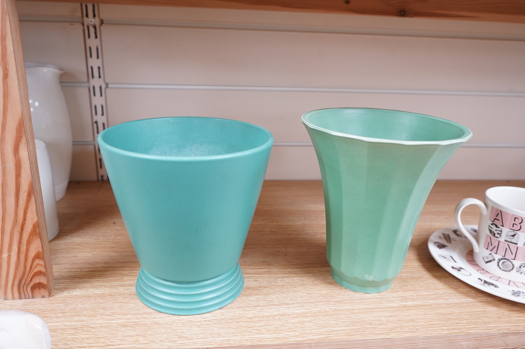 Keith Murray for Wedgwood, two green vases comprising a tapering, fluted example and one with stepped foot, largest 18cm high